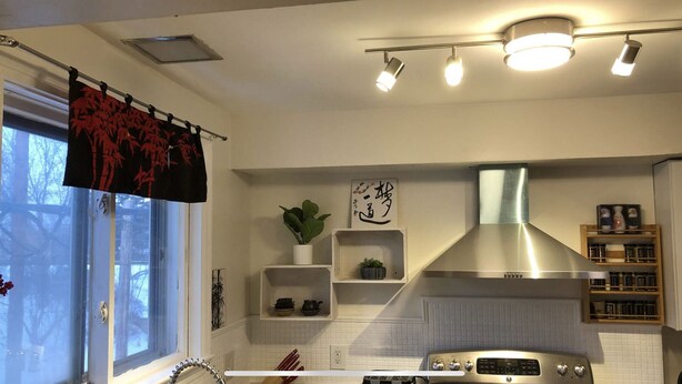 A modern kitchen with white cabinetry, a stainless steel range hood, and a window with a view of trees. - Stockade Japanese Ryokan, King bed, Washer/Dryer (Schenectady)