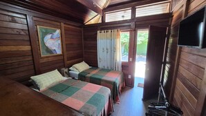 A cabin with two beds, a painting on the wall, a television, and a window with curtains. - Morada do Canal Búzios (Búzios)