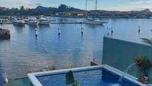 A pool with a view of a marina and distant hills. - Morada do Canal Búzios (Búzios)