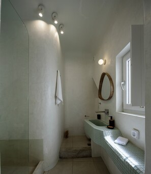 Un baño con ducha, un lavabo con espejo y una toalla colgada en la pared.