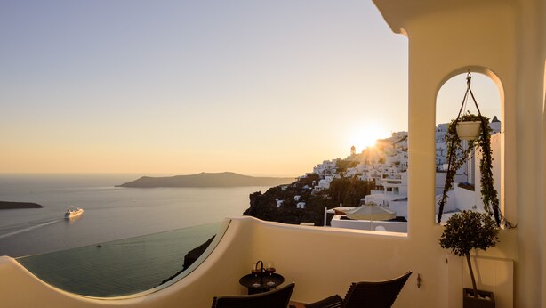 A balcony with a hot tub, two chairs, and a hanging plant. - Located at the breathtaking caldera of Imerovigli (Ημεροβίγλι)