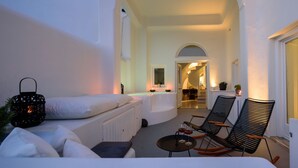 A cozy balcony with a white sofa, two rocking chairs, a small table with glasses, and a lantern. - Located at the breathtaking caldera of Imerovigli (Ημεροβίγλι)