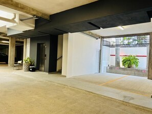 A spacious indoor area with concrete flooring, a staircase, and a large window with a view of the outside.