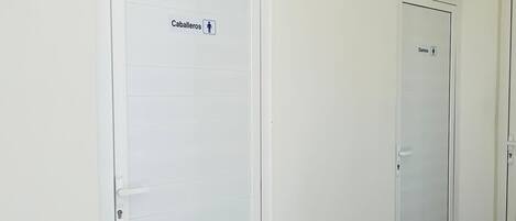 Two white doors with labels indicating "Caballeros" and "Damas" for male and female restrooms respectively.