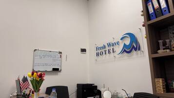 Ein Büro mit einer Whiteboard-Tafel, einem Schreibtisch mit Büromaterialien, einer Wasserflasche und einem Schild für das Fresh Wave Hotel.