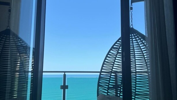 Una stanza con un'ampia vetrata che si affaccia sul mare, una sedia a dondolo e un tavolino.