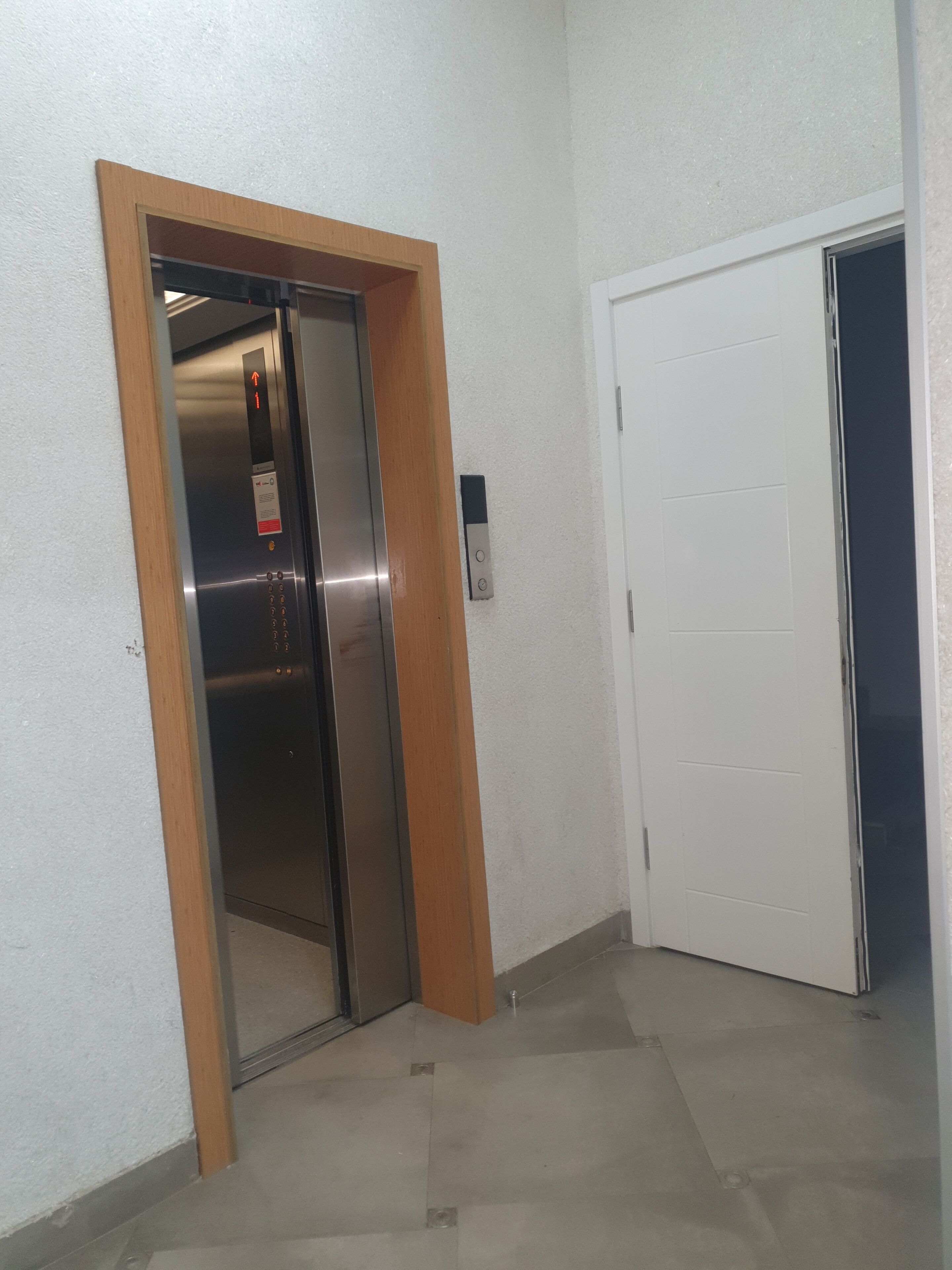 A narrow hallway with a closed elevator and a door on the right.