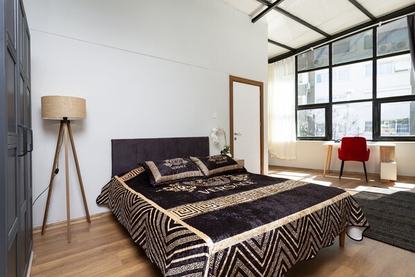 Une chambre à coucher moderne avec un grand lit, un bureau et une chaise.