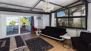 Een moderne woonkamer met een zwarte bank, een witte salontafel en een kroonluchter.