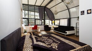 Een moderne kamer met een groot bed, een zwarte bank en een eethoek.