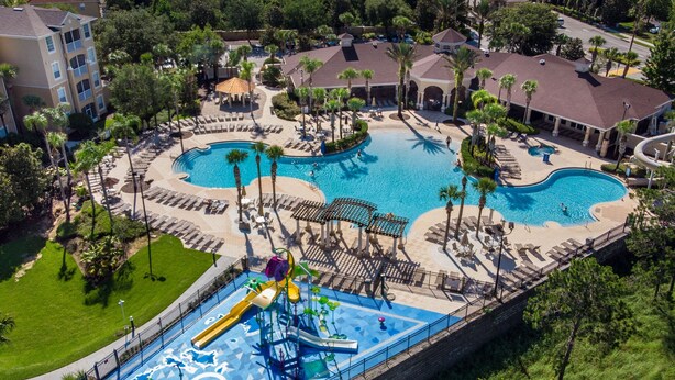 Luchtbeeld van een resort met twee zwembaden, een waterpark en omliggend groen.