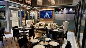 A modern dining area with a large TV, comfortable seating, and elegant decor. - Aparamento 2 Dormitorios Edificio Zetta Village Airport (Mariano Roque Alonso)