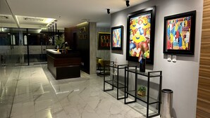 A modern hotel lobby with a reception desk, marble flooring, and contemporary art on the walls. - Aparamento 2 Dormitorios Edificio Zetta Village Airport (Mariano Roque Alonso)
