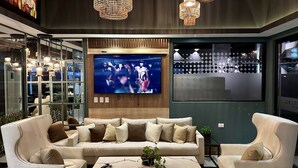 A modern living room with a large TV, comfortable seating, and stylish lighting. - Aparamento 2 Dormitorios Edificio Zetta Village Airport (Mariano Roque Alonso)