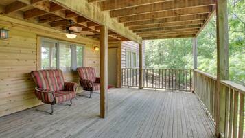 Une terrasse en bois avec deux fauteuils à rayures et un ventilateur de plafond.