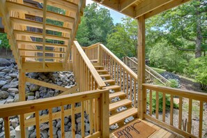 Una escalera de madera que conduce a una terraza con vistas a una zona boscosa.