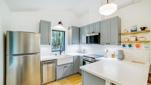 A modern kitchen with grey cabinets, stainless steel appliances, a dishwasher, and a coffee station. - Peaceful Mendocino Cottage Surrounded By Redwoods (Mendocino)