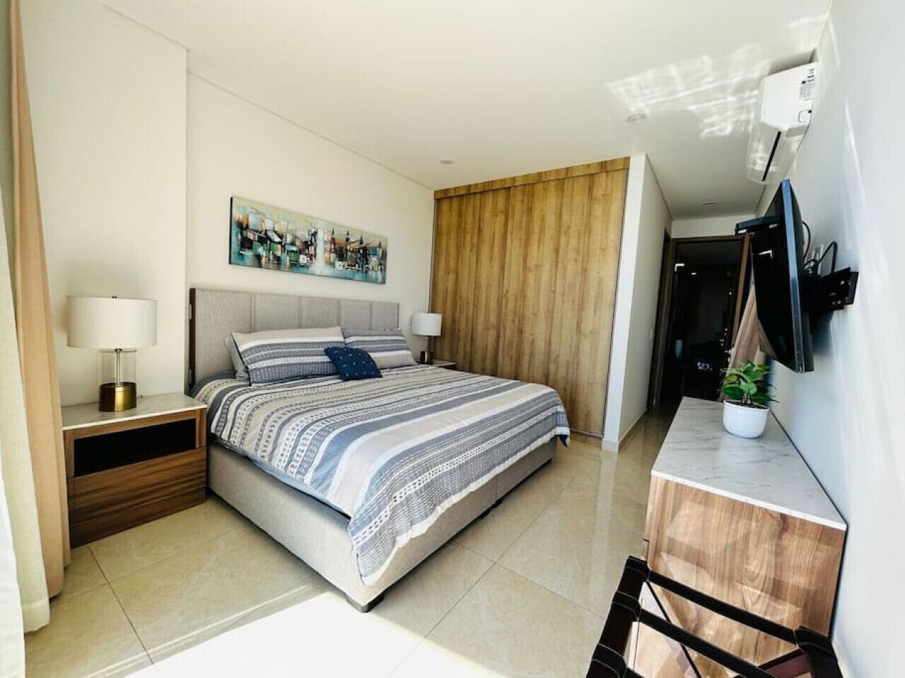 Een moderne hotelkamer met een groot bed, een bureau, een televisie en een schilderij aan de muur.
