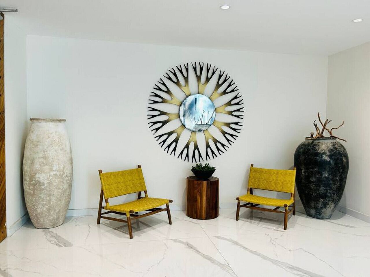 A reception area with two yellow chairs, a large vase, and a wall-mounted circular artwork.