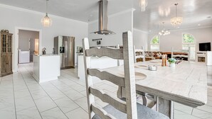 Eine geräumige Küche mit Kochinsel, Edelstahlgeräten und Pendelleuchten.