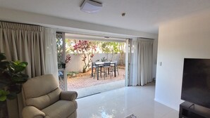 Un salon comprenant un canapé, un téléviseur et un coin repas avec une table et des chaises.