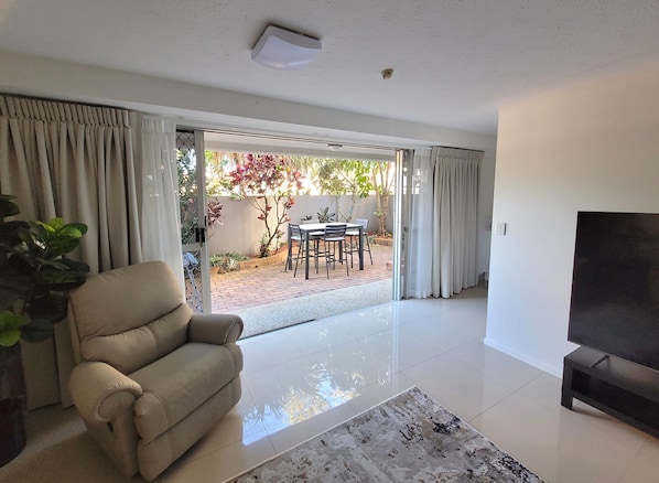 A living room with a sofa, a TV, and a dining area with a table and chairs.