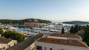 Una marina con numerose imbarcazioni ormeggiate, circondata da edifici e colline.