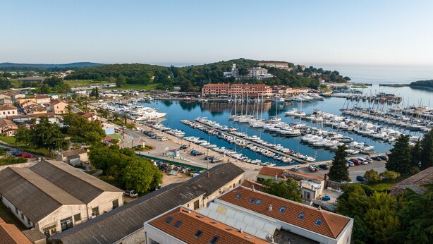 Una marina con numerose imbarcazioni ormeggiate, circondata da edifici e vegetazione.