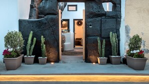 Une entrée moderne, avec un arc en pierre, une enseigne indiquant « 23 Smart Suite », et des cactus en pot de chaque côté.