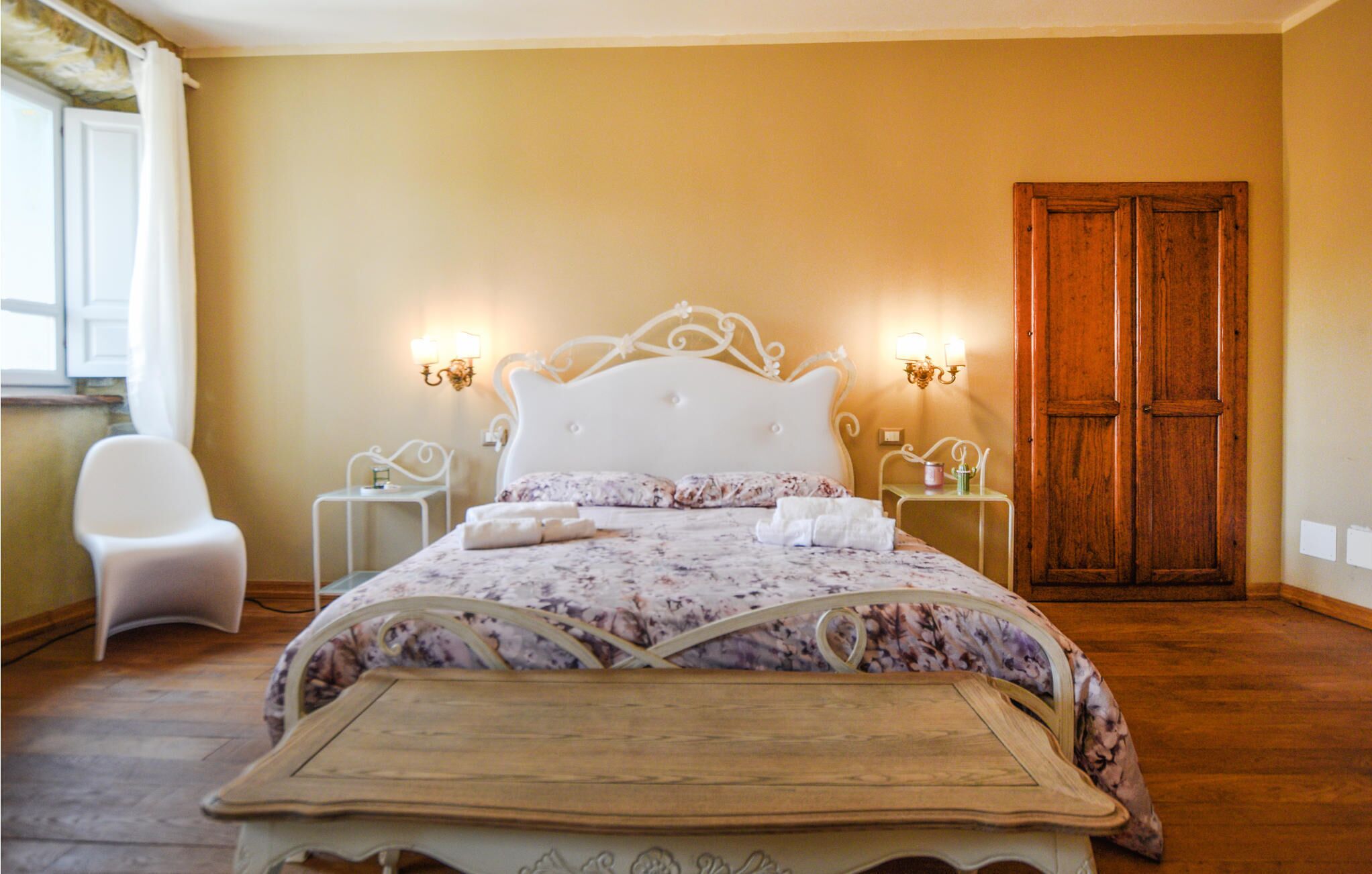 A neatly arranged bedroom with a bed, bedside tables, a chair, and a wooden door.