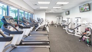 Ein Fitnessstudio mit Laufbändern, Crosstrainern und Gewichten.