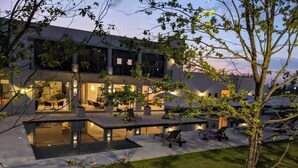 Een modern gebouw met een zwembad, terras en verzorgde tuin.