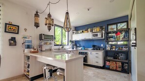 Een moderne keuken met een centraal eiland, roestvrijstalen apparatuur en een blauwe accentmuur.