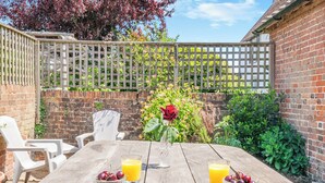A wooden table with two glasses of orange juice and bowls of cherries, surrounded by white plastic chairs. - A stunning one bedroom property in a great location with some fantastic views. (Hailsham)