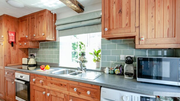 A kitchen with wooden cabinets, a washing machine, a microwave, and a sink. - A stunning one bedroom property in a great location with some fantastic views. (Hailsham)
