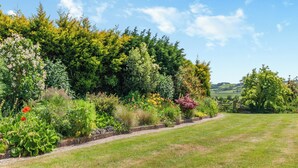 A garden with a variety of plants and flowers, a stone pathway, and a grassy area. - A stunning one bedroom property in a great location with some fantastic views. (Hailsham)