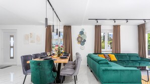 En moderne stue med en grøn sofa og et spiseområde med et træbord og stole.