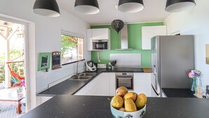 A modern kitchen with white cabinets, a black countertop, and a bowl of fruit. - Villa Frangipanier with private pool (Case-Pilote)