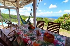 A patio with a table set for dining, a hammock, and a view of the ocean.