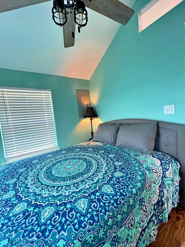 A bedroom with a bed, a ceiling fan, a window with blinds, and a wall-mounted lamp. - Pink Flamingo (Freeport)