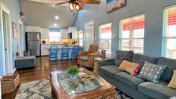 A spacious living area with a ceiling fan, a wooden coffee table, and a grey sofa. - Pink Flamingo  (Freeport)