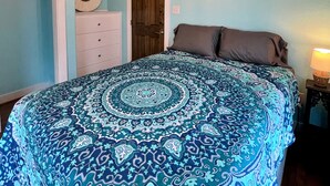 A bedroom with a ceiling fan, a bed with a patterned bedspread, a dresser, and a mirror on the wall. - Pink Flamingo  (Freeport)