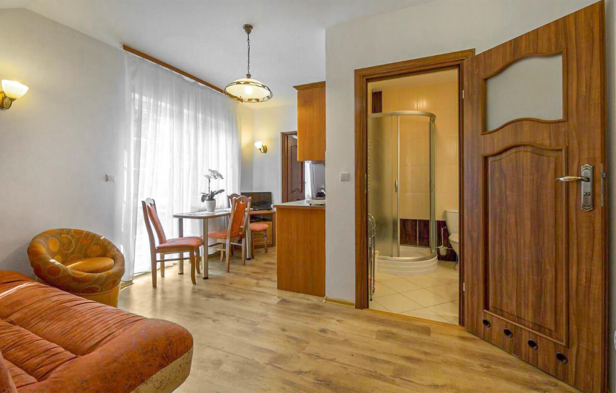 Un salon moderne comprenant un canapé, un coin repas et une cuisine visible à travers une porte ouverte.