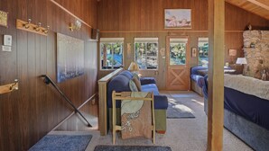 A cozy cabin interior with wooden walls, a stone fireplace, and a bed with blue bedding.