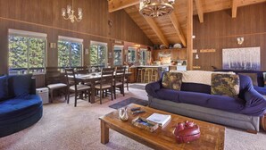 A cozy cabin interior with a dining area, a living room with a sofa and a coffee table, and a kitchen.