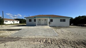 A two-story building with a concrete driveway and gravel ground. - Rolleville Darling House - 2 minute walk from the beach! (Exuma)