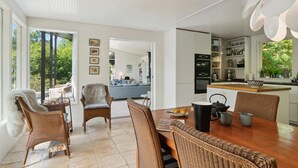 Una cocina moderna con comedor, que cuenta con una isla grande, electrodomésticos integrados y vistas al exterior.