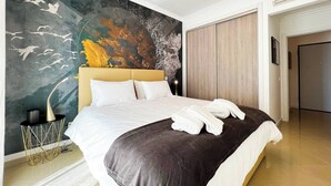Une chambre d’hôtel moderne avec un grand lit, une fresque murale et une armoire en bois.