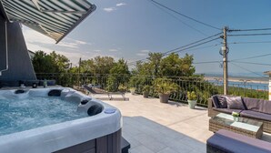 Un jacuzzi con vista al mar, mobiliario exterior y plantas en macetas.