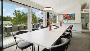 Un comedor moderno con una mesa larga, sillas negras y un jarrón con flores.